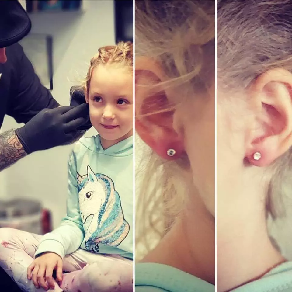 A little girl is piercing her ear.