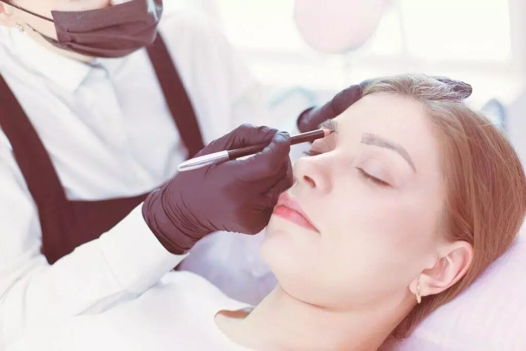 A woman getting her eyebrows done at a salon.