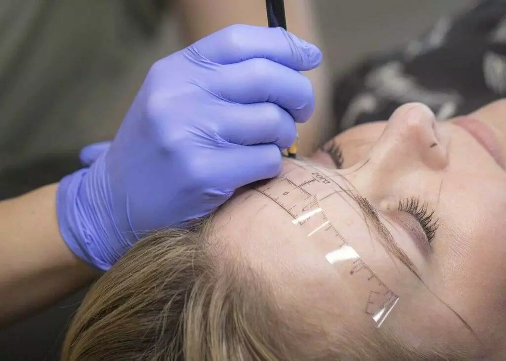 A woman undergoing microblading for her eyebrows.