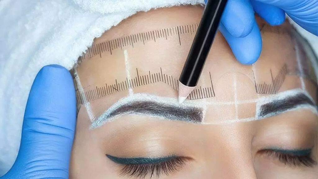 A woman is getting her eyebrows tattooed at home.