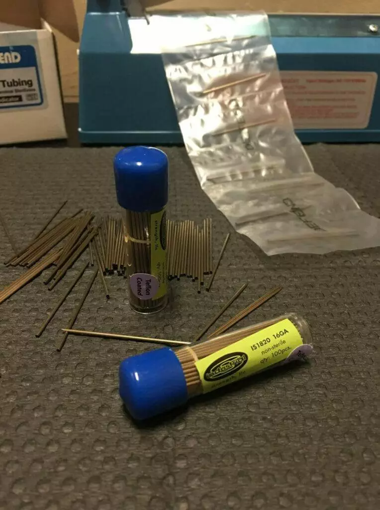 A tube of tweezers on a table used for piercing.